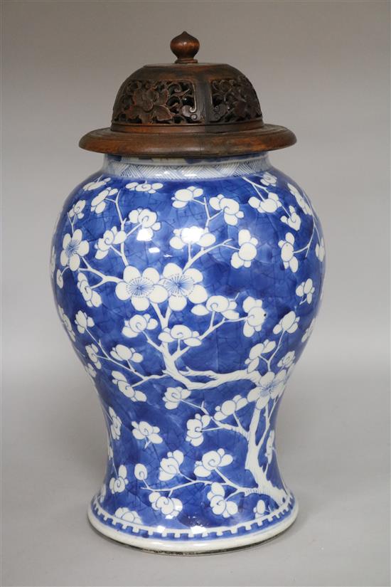 A 19C Chinese blue and white inverted pyriform vase, decorated prunus, with carved pierced hardwood cover